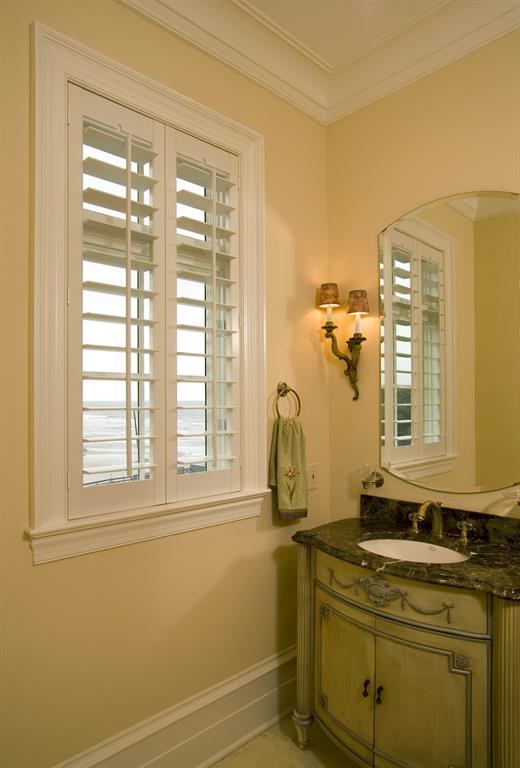 White plantation shutters in a bathroom looking out over ocean